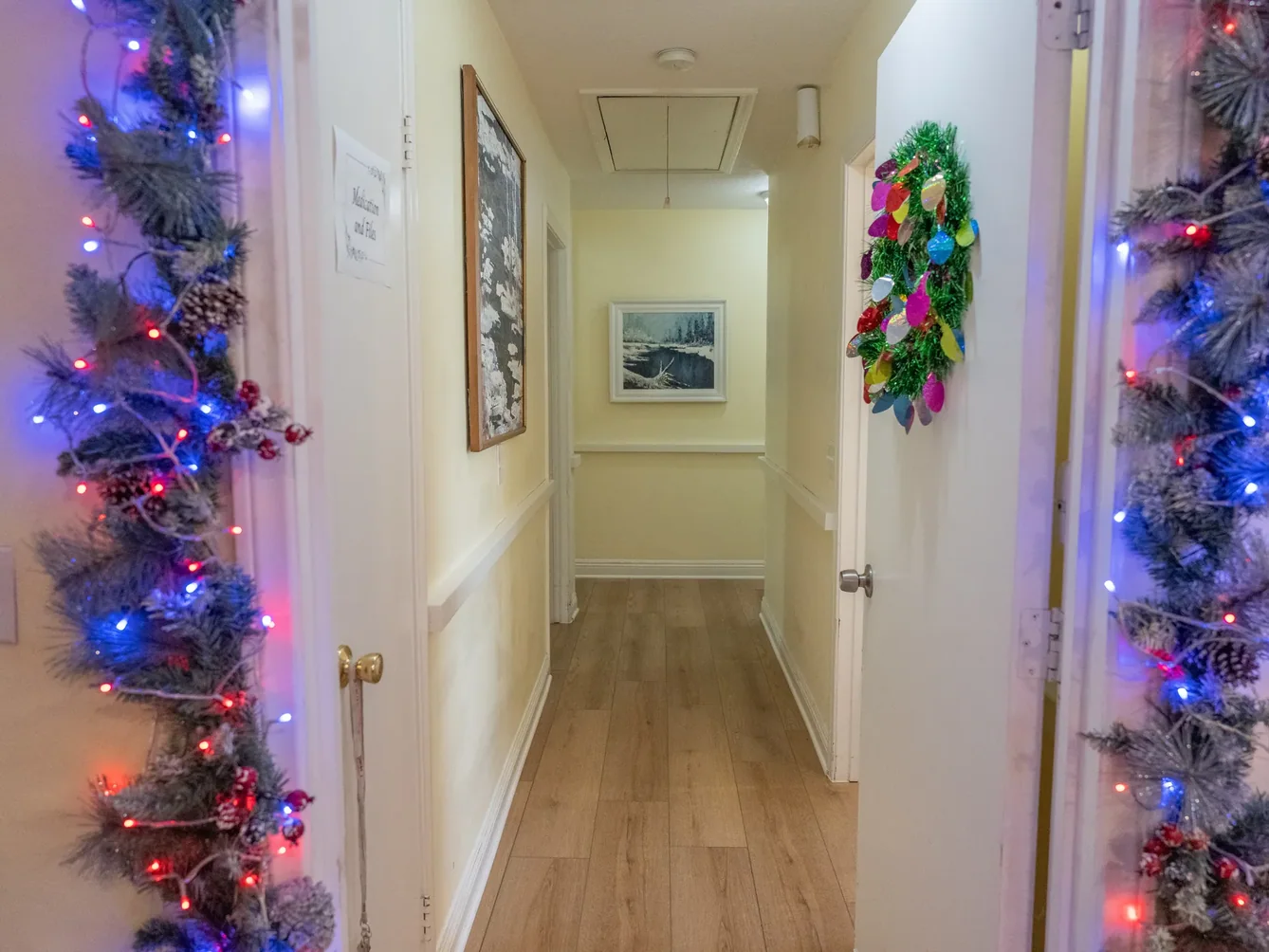 Bright hallway in residential care facility decorated with festive garland and multicolored Christmas lights on both sides