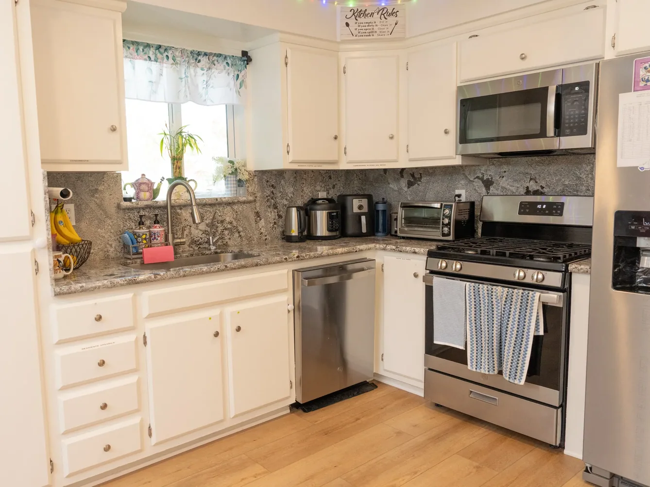 Accessible residential care facility kitchen featuring white cabinetry, granite countertops, and modern stainless steel appliances