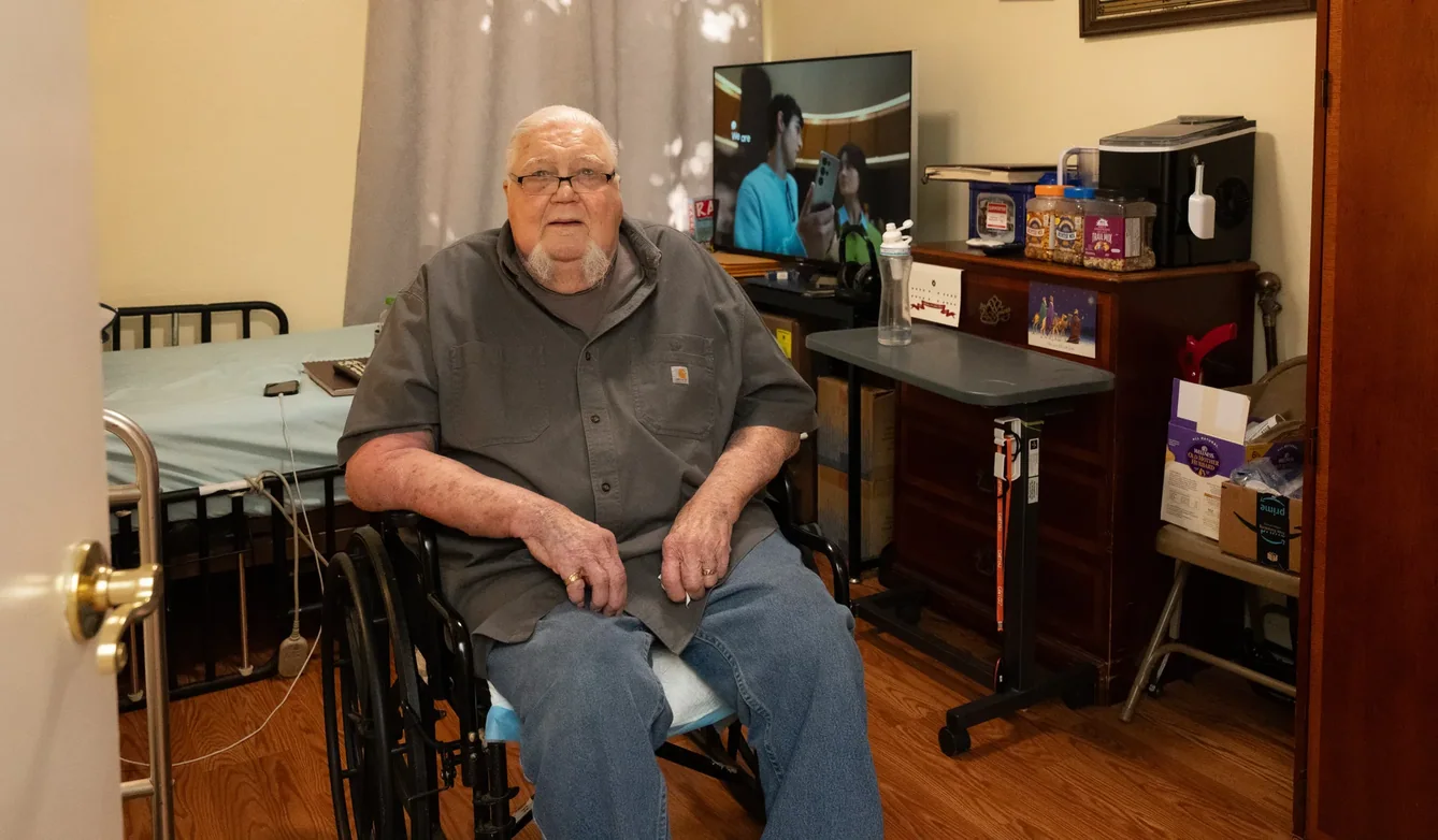 Resident relaxing in wheelchair in comfortable private room with accessible amenities and entertainment options